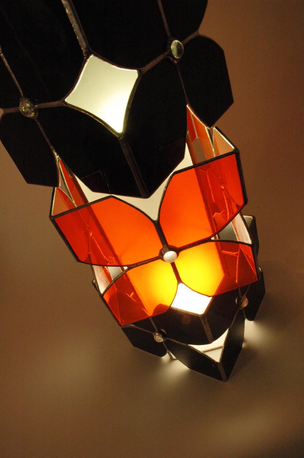 Vitraux oranges et noirs pour cette lampe à poser. Equipée de deux ampoules elle constitue une source de lumière intéressante en lampe d'appoint intégrée à la déco, sur un bureau ou une table de chevet.